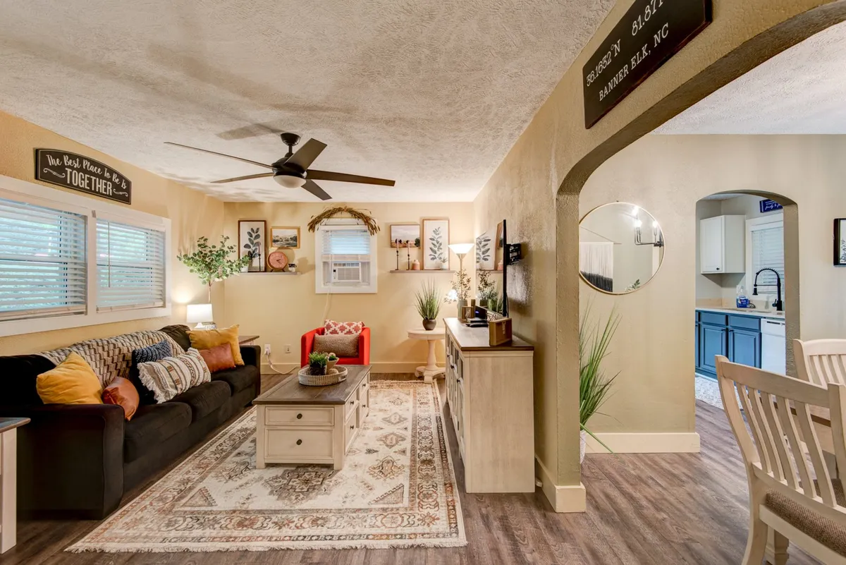 A cozy interior living area featuring a plush sofa and coffee table, with the kitchen entrance visible in the background. The scene evokes relaxation, making it an ideal spot for family gatherings, movie nights, or board games after a day of adventure.