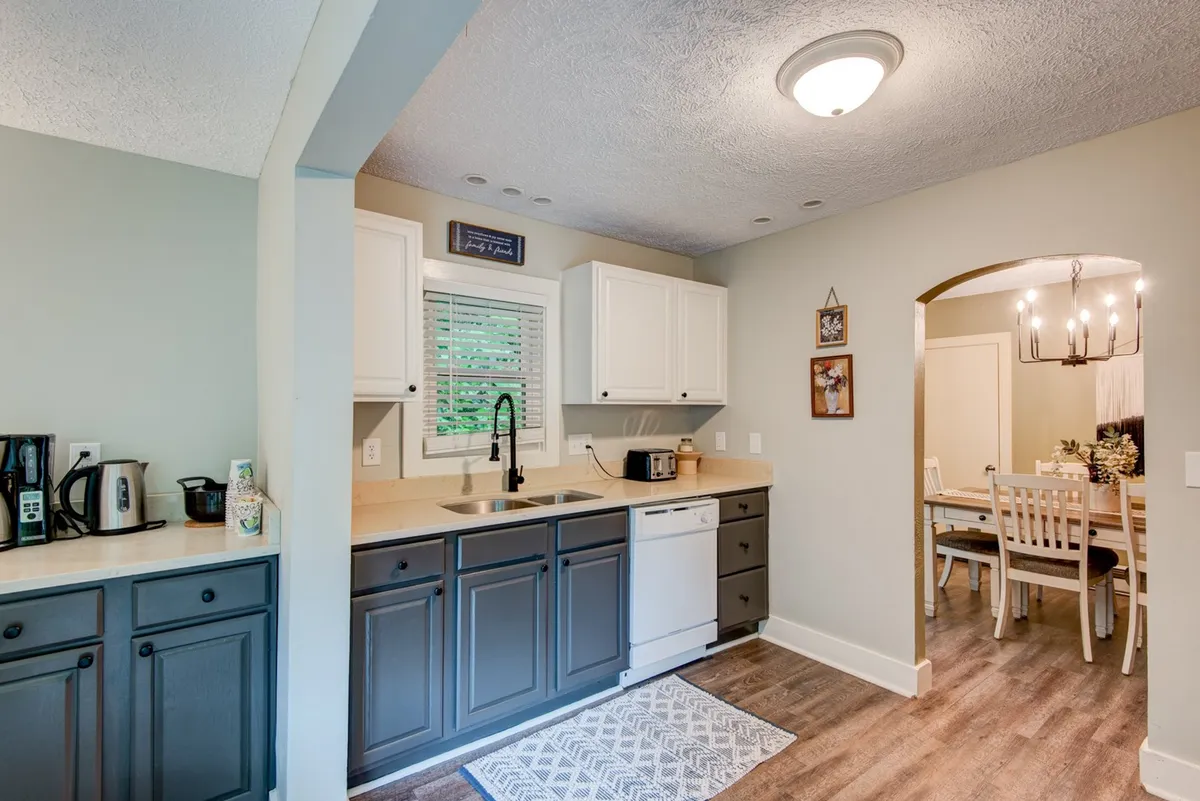 This image captures the inviting kitchen and dining area of Hot Toddy Cottage, featuring a welcoming island, comfortable seating, and warm lighting. The layout suggests a space perfect for gathering after a day’s adventure, with visible amenities that encourage cooking, entertaining, and sharing meals.